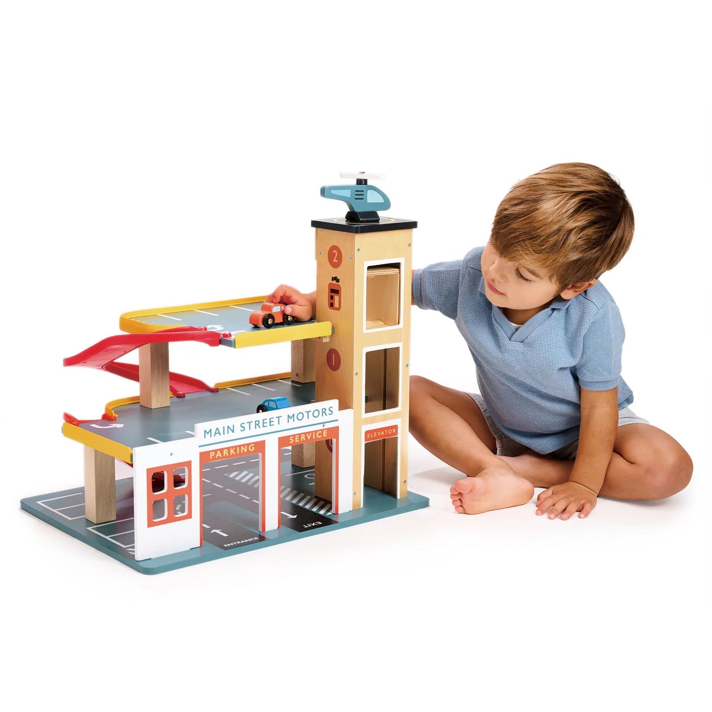 Child playing with a toy garage set on a white background