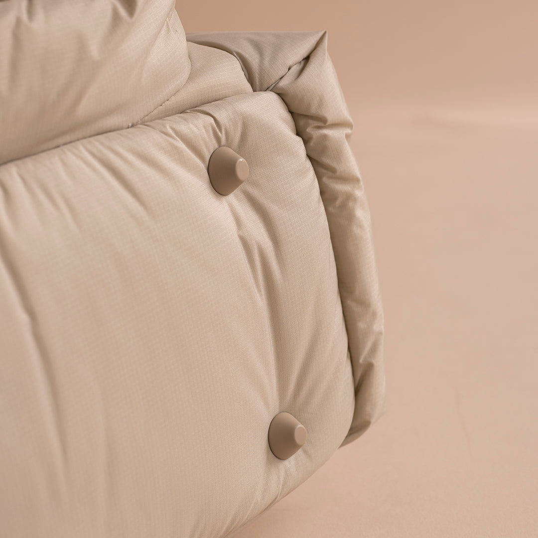 Close-up of a beige quilt with button details on a beige background