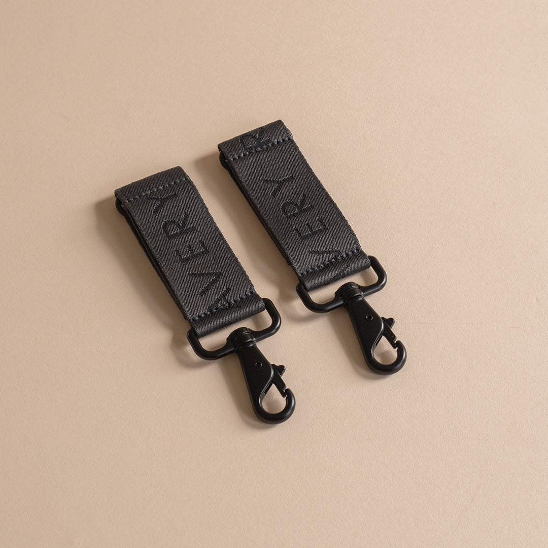 Two black leather straps with 'VERY' branding on a beige background