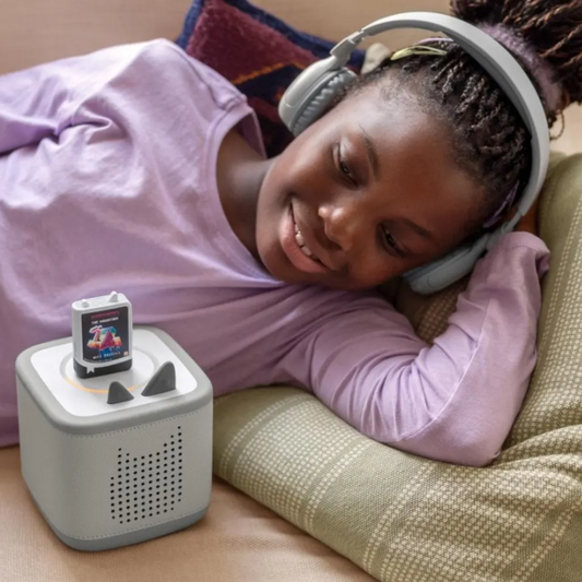 Child wearing headphones next to a music device on a couch