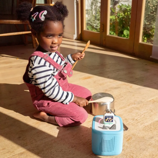 Child playing with toy kitchen set on a wooden floor