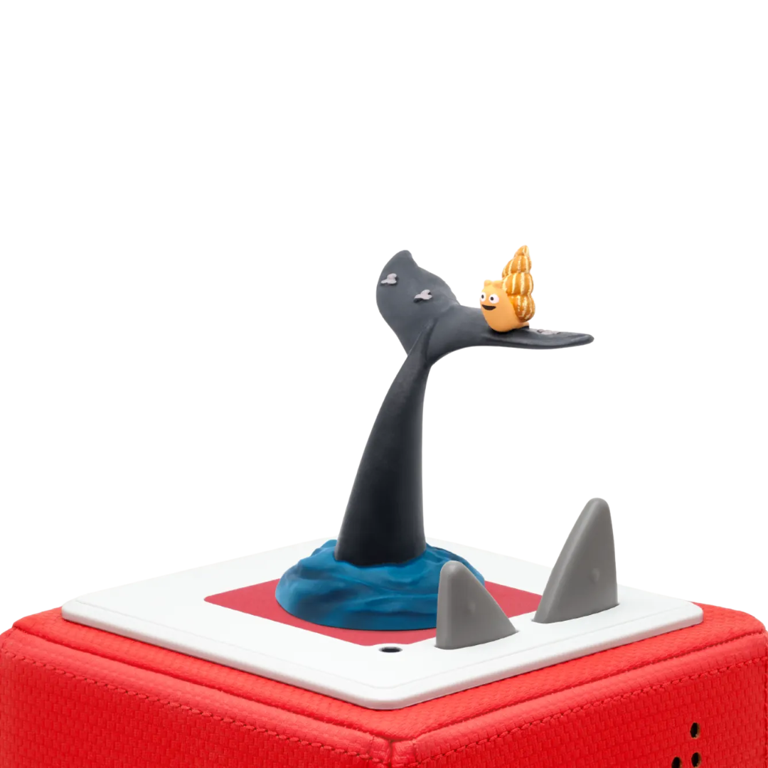 Toy figure of a whale with a small character on its back, sitting on a red and white base.