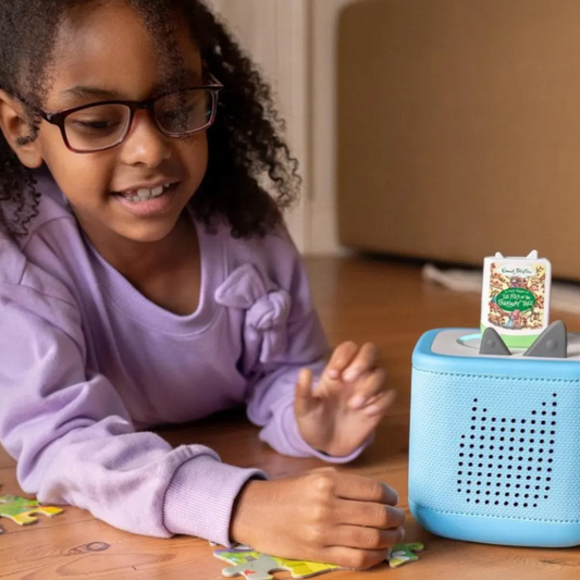 Child playing with a blue toy device on a wooden table