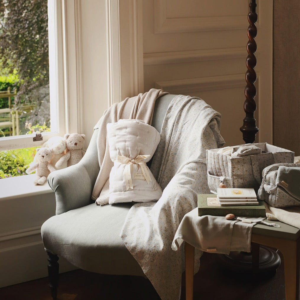 Cozy armchair with soft pillows and blankets in a room with a window view.