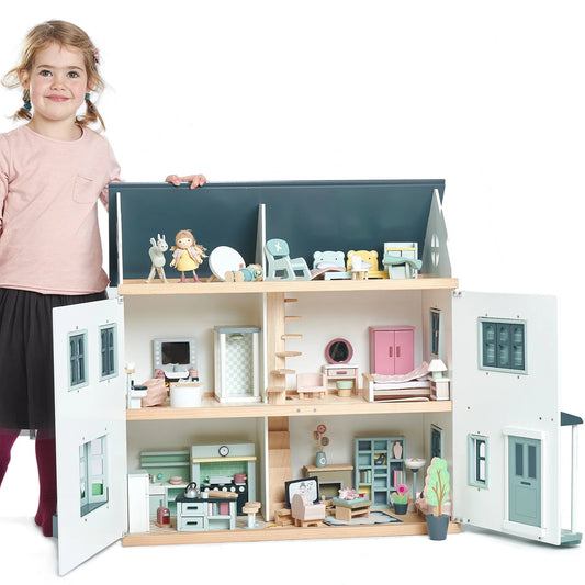Child with a large dollhouse and accessories on a white background