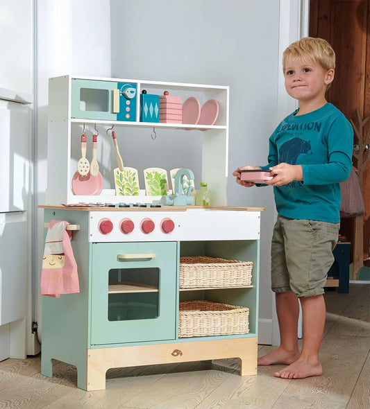 Child playing with a toy kitchen set in a home setting