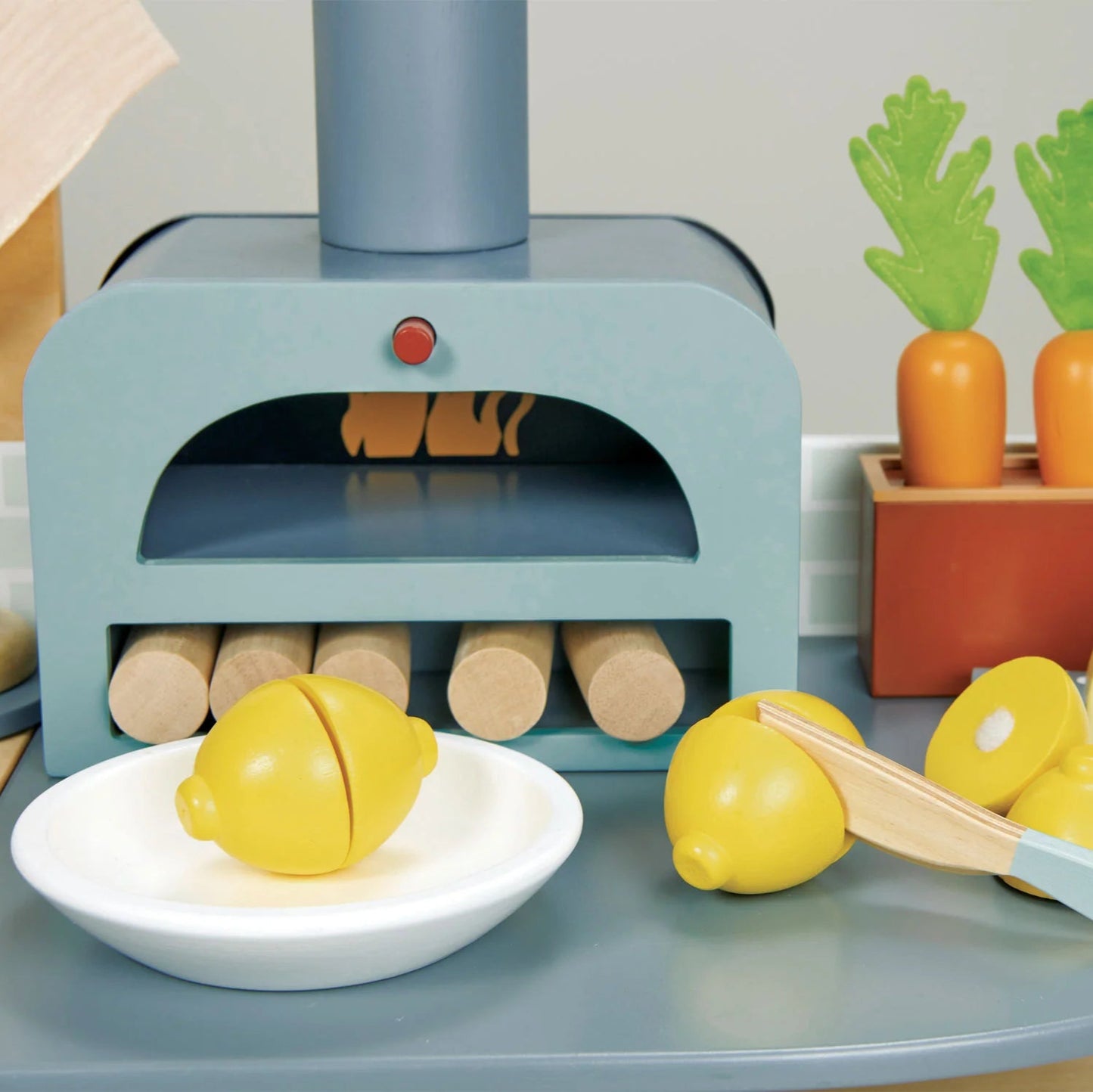Toy kitchen set with oven, fruits, and vegetables on a table.