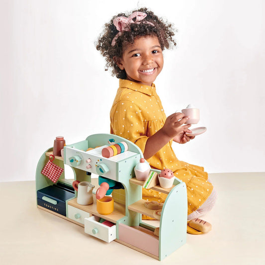 Child playing with a toy kitchen set on a white background