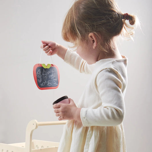 Child holding a small chalkboard with a red frame and green leaves, standing against a plain background.