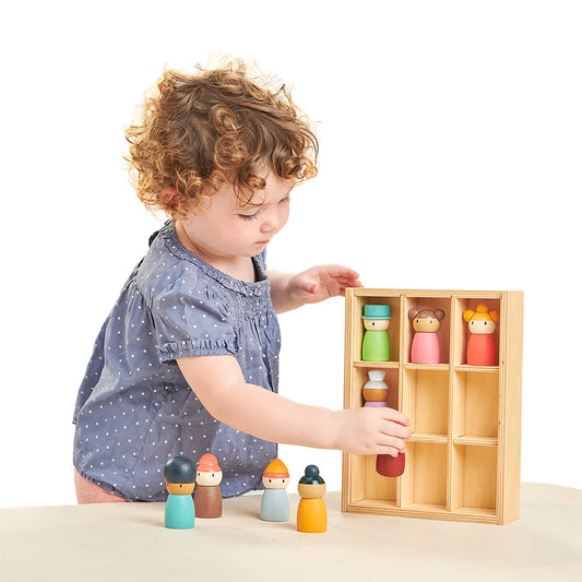 Child playing with wooden toy figures in a box on a white background