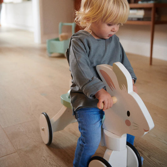 Child playing with a wooden toy horse indoors