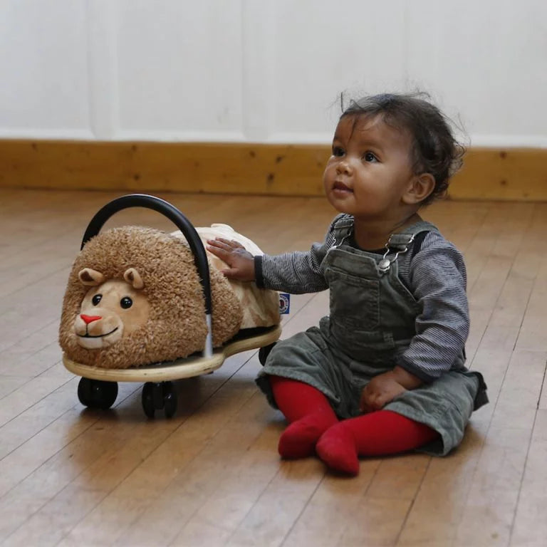 Child playing with a lion-shaped toy on a wooden floor