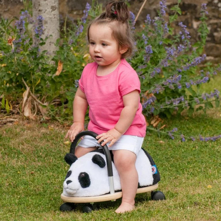 Child sitting on a panda-shaped toy in a grassy area