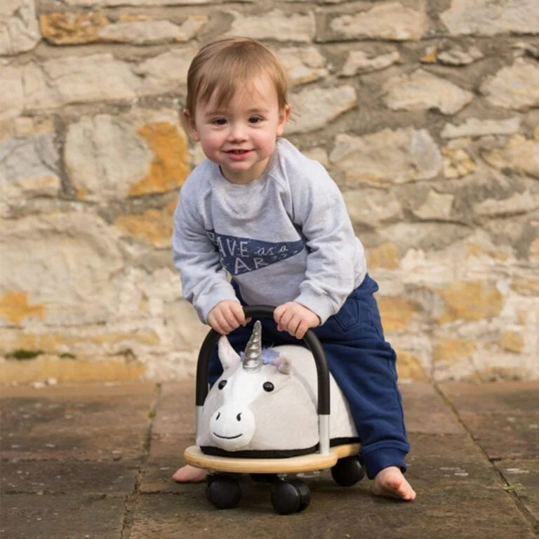 Young girl sitting on a toy horse outdoors