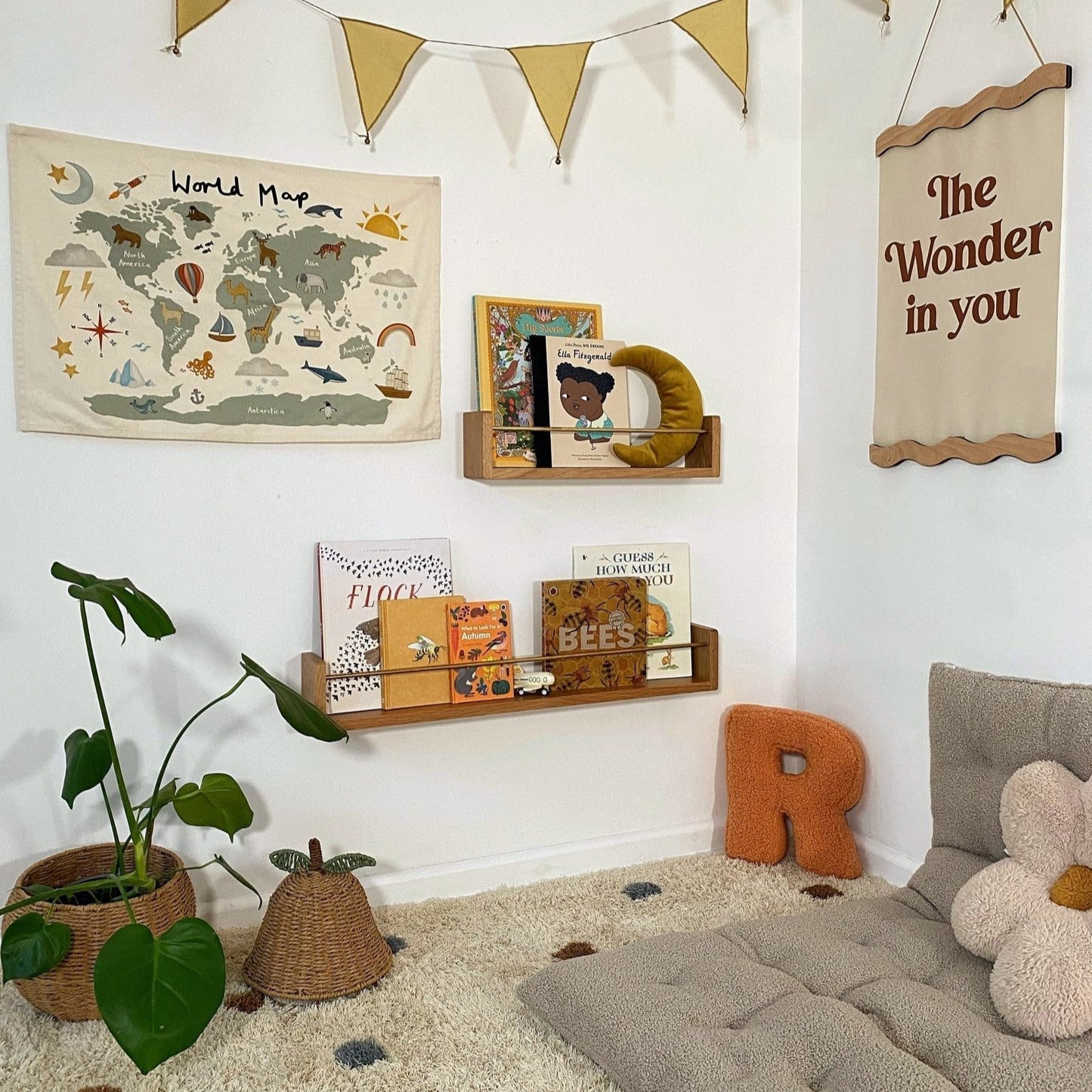 Children's room with world map, books, and decorative elements on a white wall.