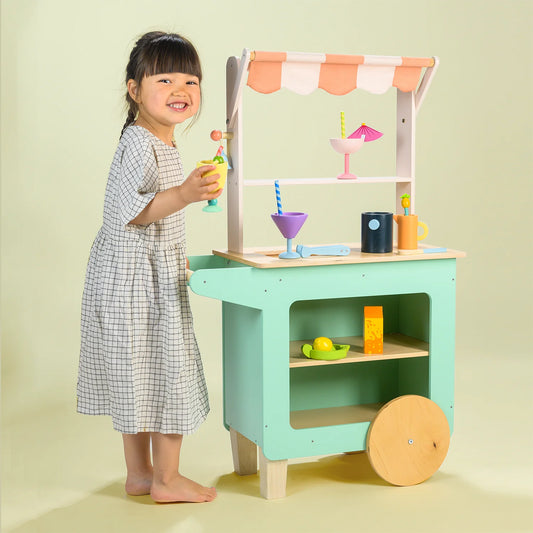 Child playing with a toy kitchen set on a light green background
