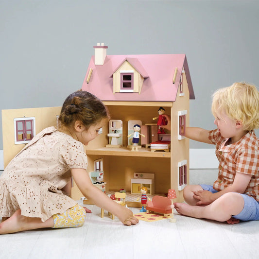 Two children playing with a dollhouse on a plain background