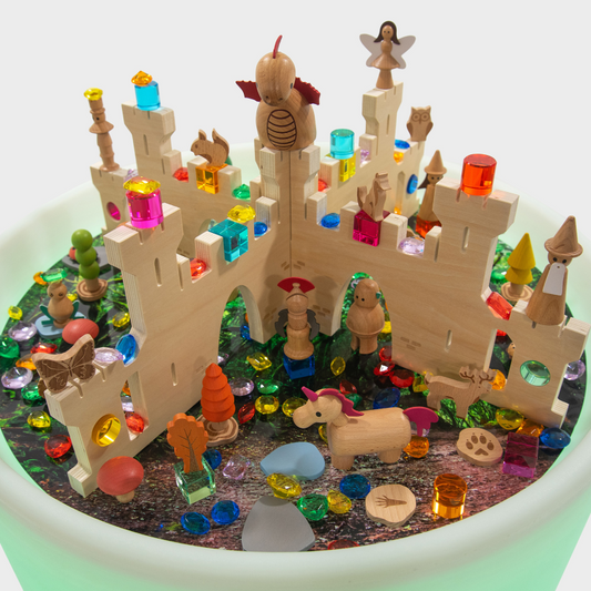 Wooden toy castle with colourful blocks and figurines on a sensory table
