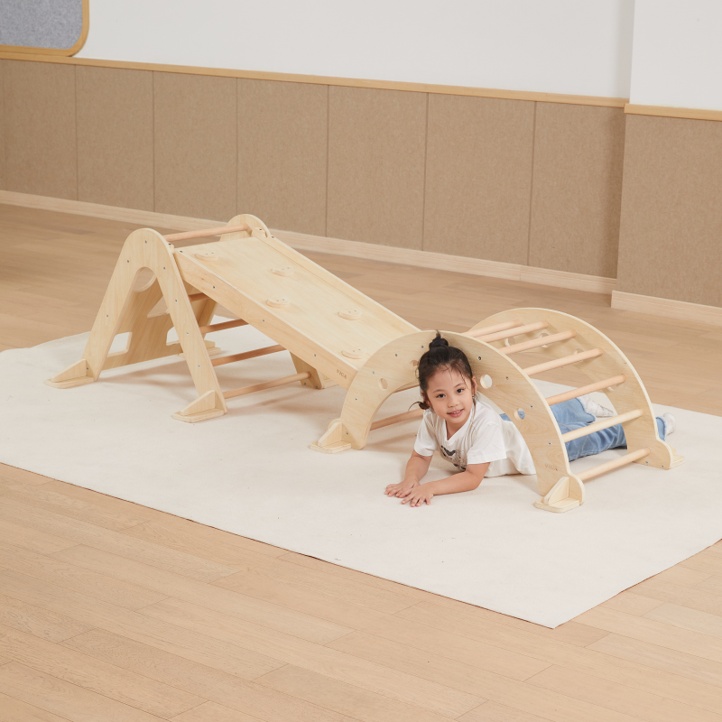Child playing on a wooden climbing toy indoors