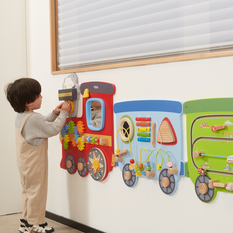 Child interacting with a colorful train-shaped educational wall toy.