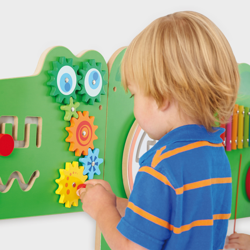 Child playing with a colourful educational board featuring gears and shapes.