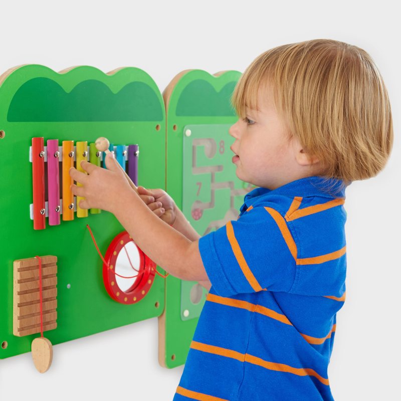 Child playing with a colourful wooden toy wall panel with educational toy on a white background