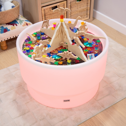 Dinosaur playscene with a wooden volcano set up on a sensory mood light table