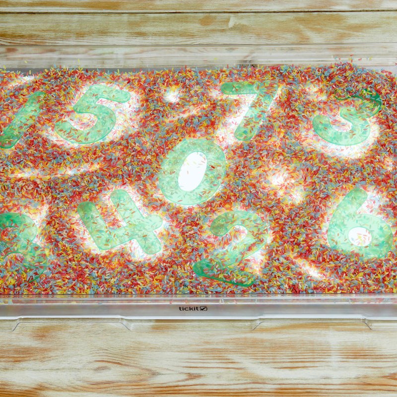 sensory rice with plastic numbers in a tray over a light panel