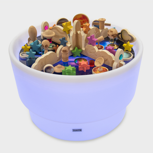 Wooden toy set with colorful stars and sea creatures in a light up sensory light table on a white background