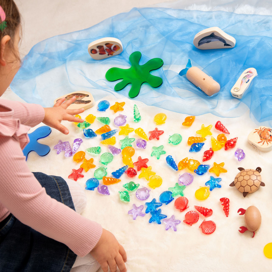 A child playing with sensory sea creatures and wooden animal figures.