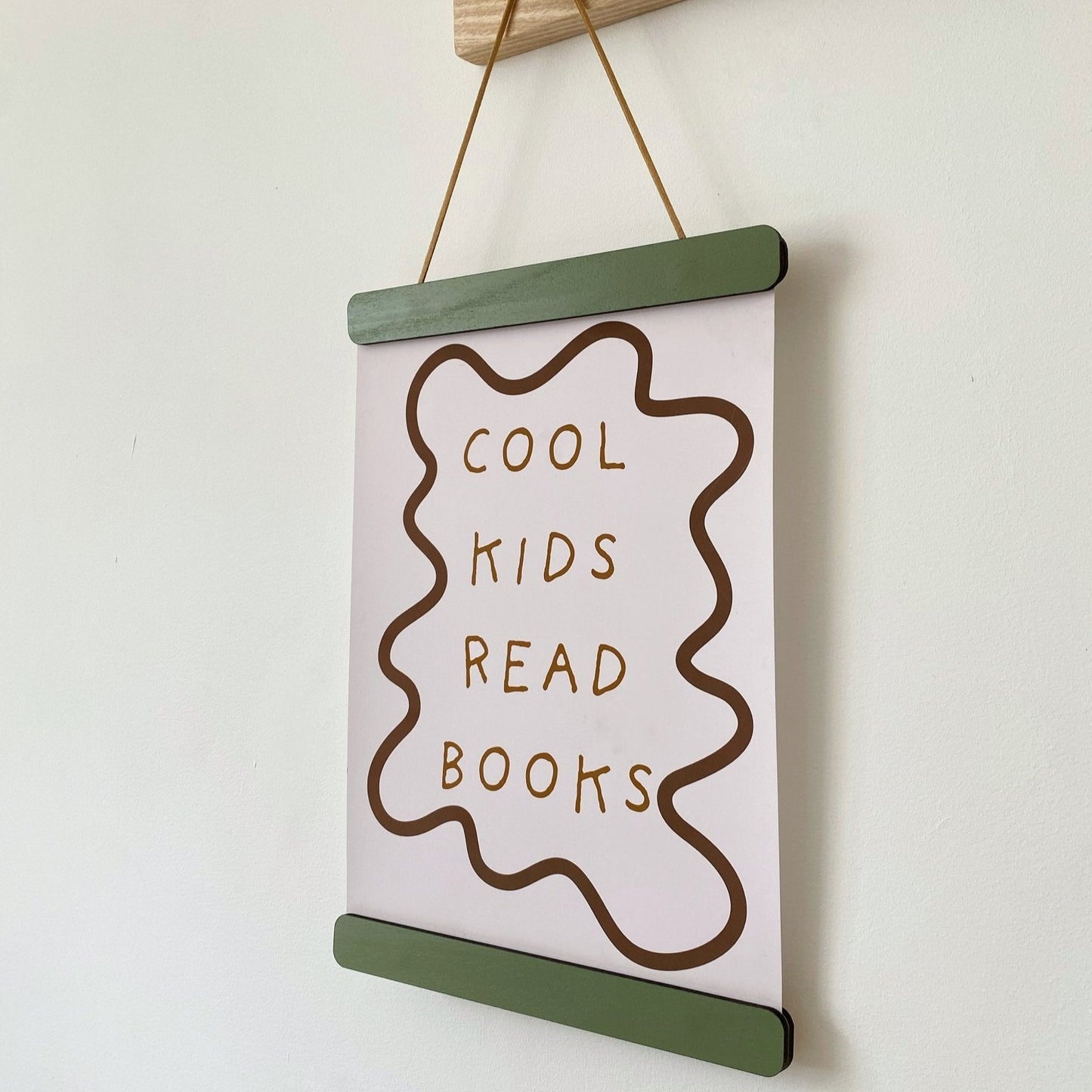 Hanging sign with 'Cool kids read books' text on a white wall