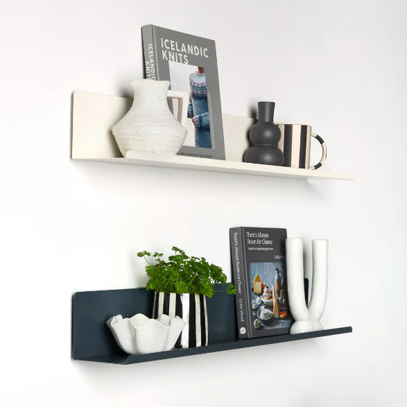 Decorative shelves with books, vases, and plants against a white wall.