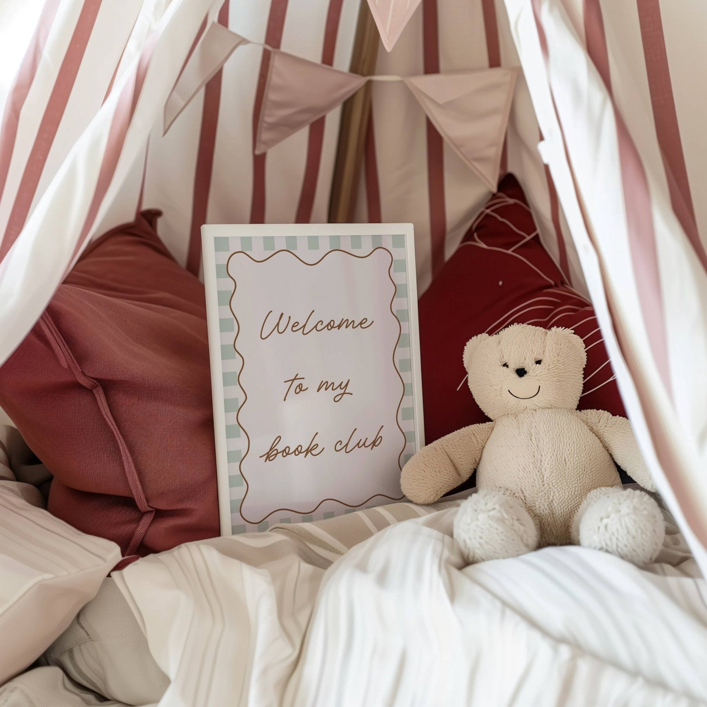 Children's reading nook with teddy bear, pillows, and 'Welcome to my book club' sign.