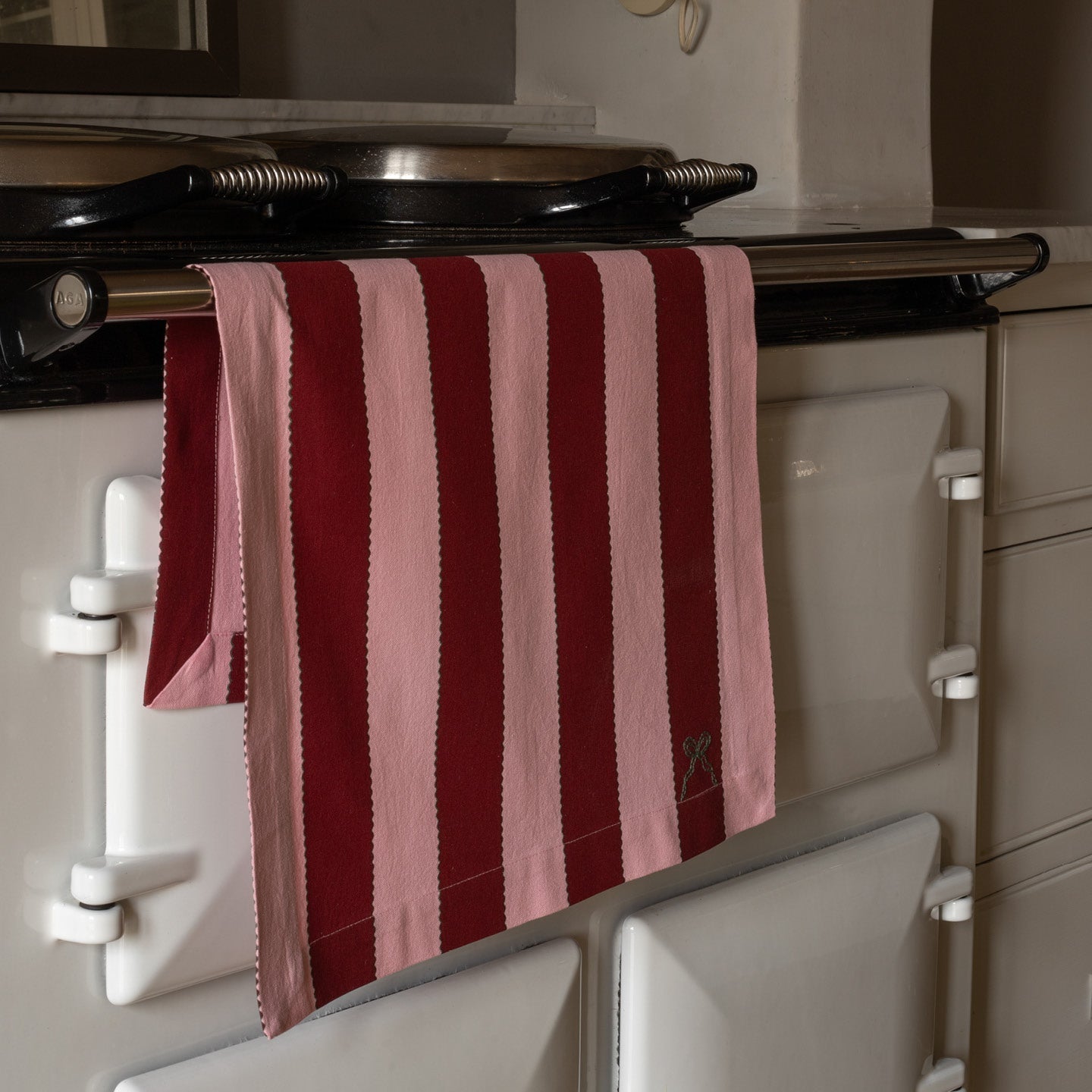 Striped red and pink towel hanging on a vintage-style oven.