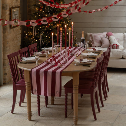 Dining room set for a festive meal with a Christmas tree in the background.