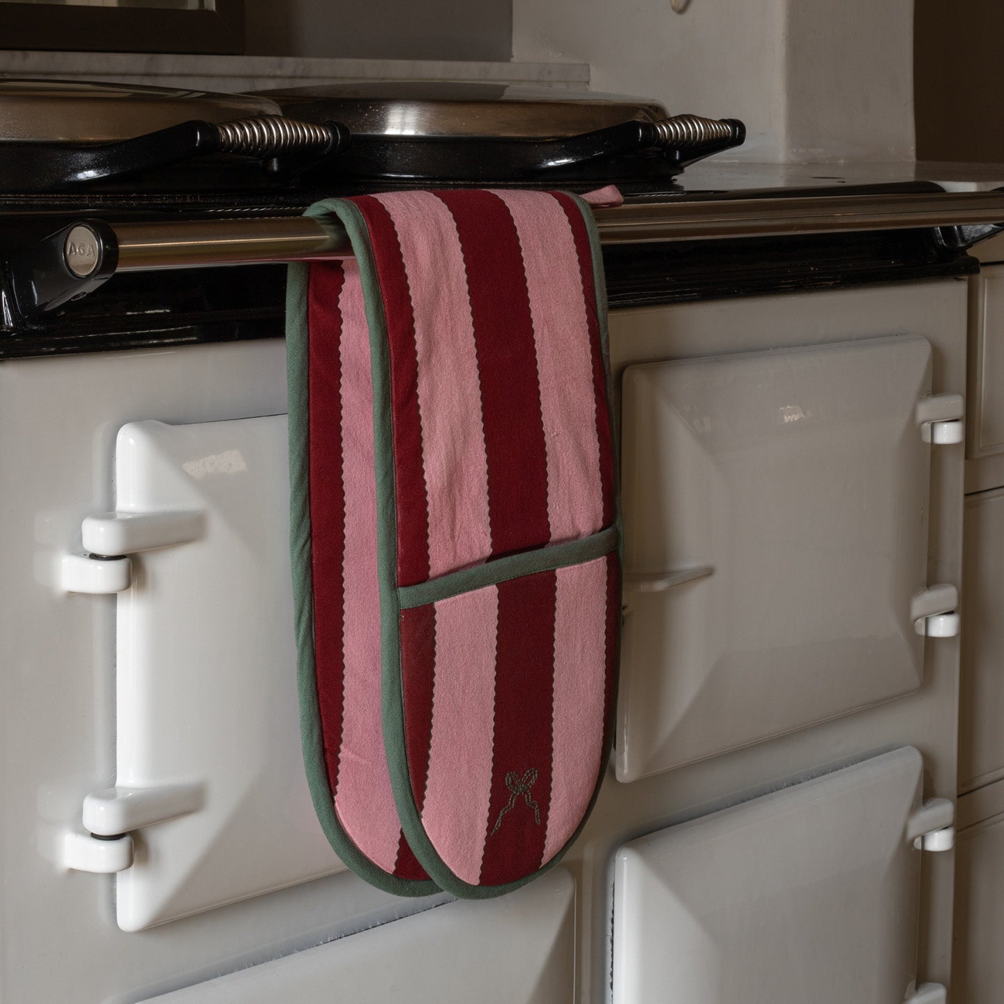 Red and green striped oven mitt hanging on a white stove.