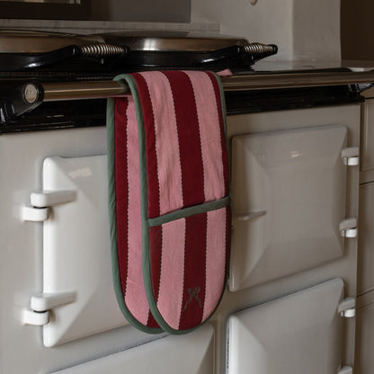 Red and green striped oven mitt hanging on a white stove.