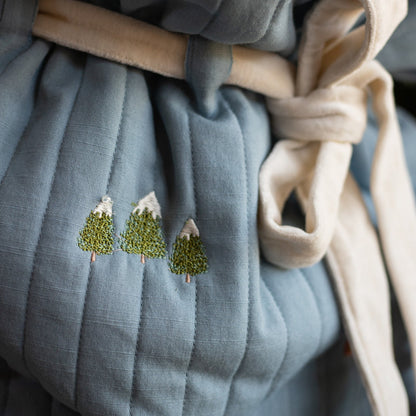 Embroidered trees on a textured fabric surface
