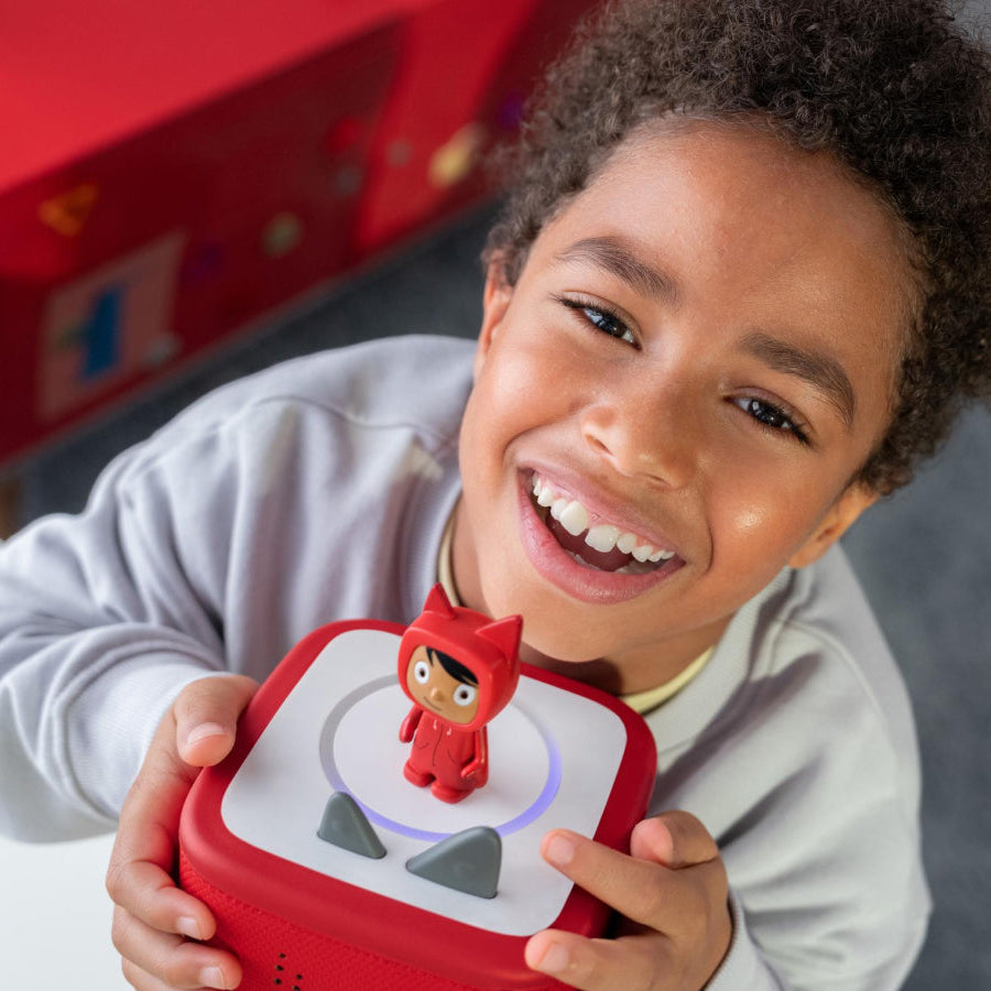 Child holding a red toy device with a character on it, smiling.