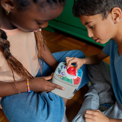 Two children playing with a toy on a wooden floor.