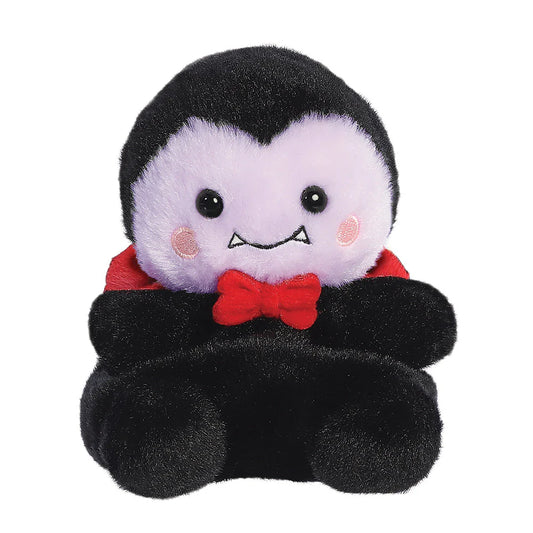 Plush toy vampire with black hair, white face, red bow tie, and black cape on a white background