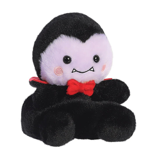 Plush toy resembling a vampire with a red bow tie on a white background