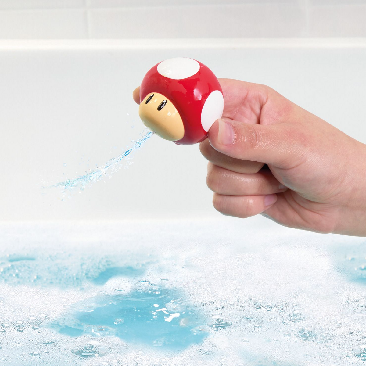 Hand holding a red mushroom-shaped water gun over water