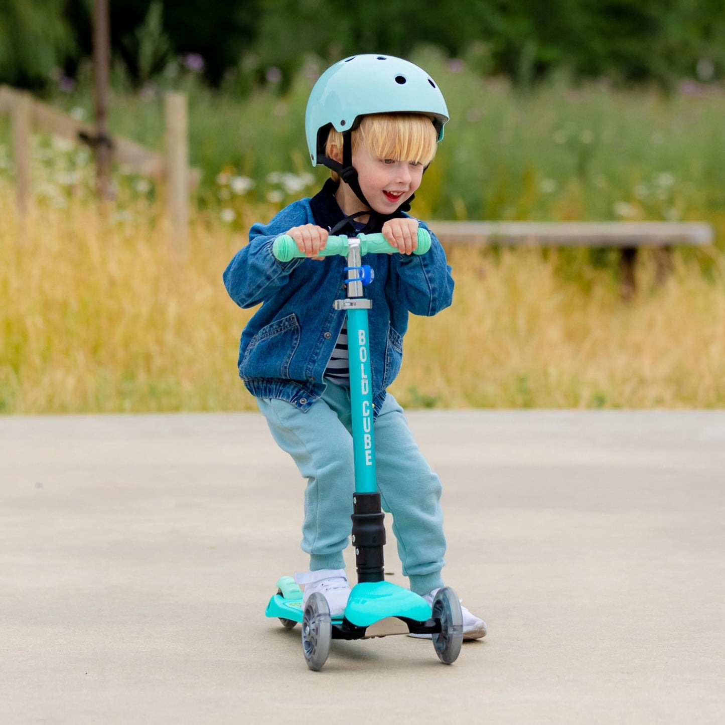 Child riding a scooter with a helmet in an outdoor setting