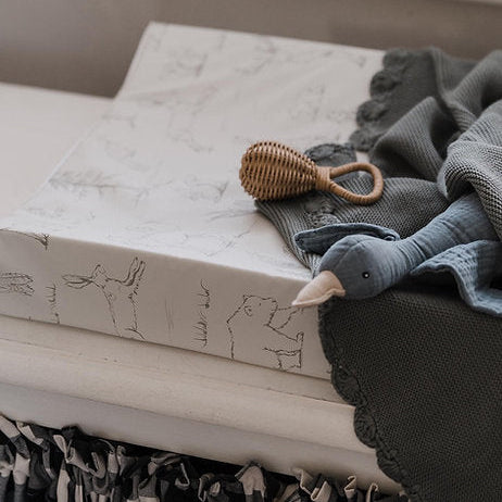Baby items including a rattles and soft toys on a textured surface.