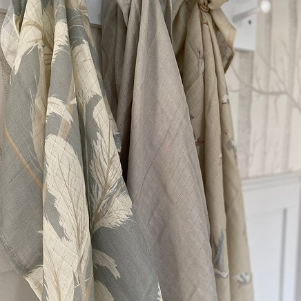 Set of three fabric swatches with different patterns and colors hanging against a neutral background.