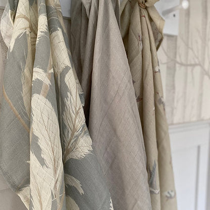 Set of three fabric swatches with different patterns and colors hanging against a neutral background.