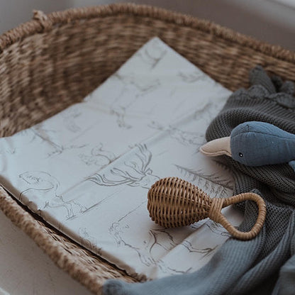 Wicker basket with baby items including a rattles and soft toys on a marble surface
