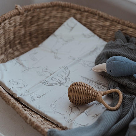 Wicker basket with baby items including a rattles and soft toys on a marble surface