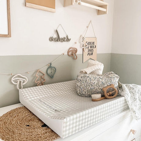 Nursery room with changing table, toys, and decorative elements on a light green wall.